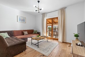Un salon moderne avec un canapé marron, une table basse en bois et une grande porte-fenêtre coulissante donnant sur un espace extérieur.