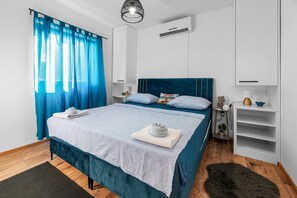 Un dormitorio moderno con cama, mesita de noche, cómoda y unidad de aire acondicionado.
