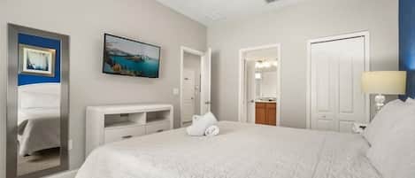 Habitación de hotel con una cama grande, ventilador de techo, un cuadro en la pared y la puerta del baño.
