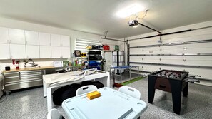 Eine Garage mit Tischtennisplatte, Kicker und Stauraumschränken.