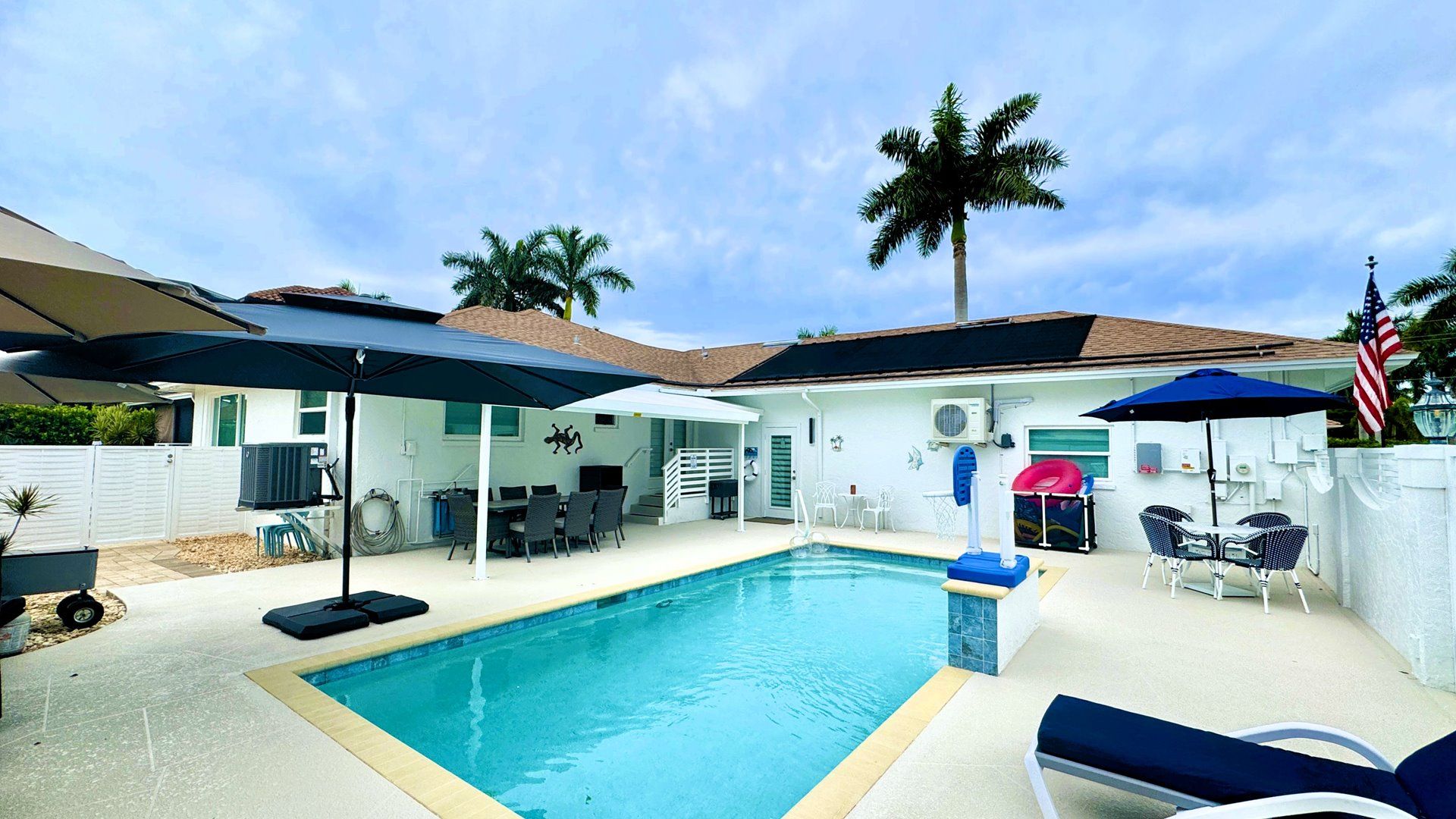 A backyard with a swimming pool, outdoor furniture, and a covered patio area.