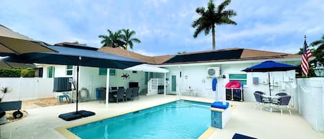 Un jardin avec une piscine, du mobilier d’extérieur et un patio couvert.