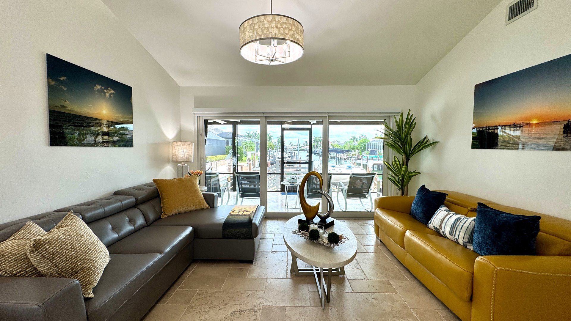 Un salon moderne avec un canapé, un divan jaune, une table basse et une grande fenêtre donnant sur l’extérieur.