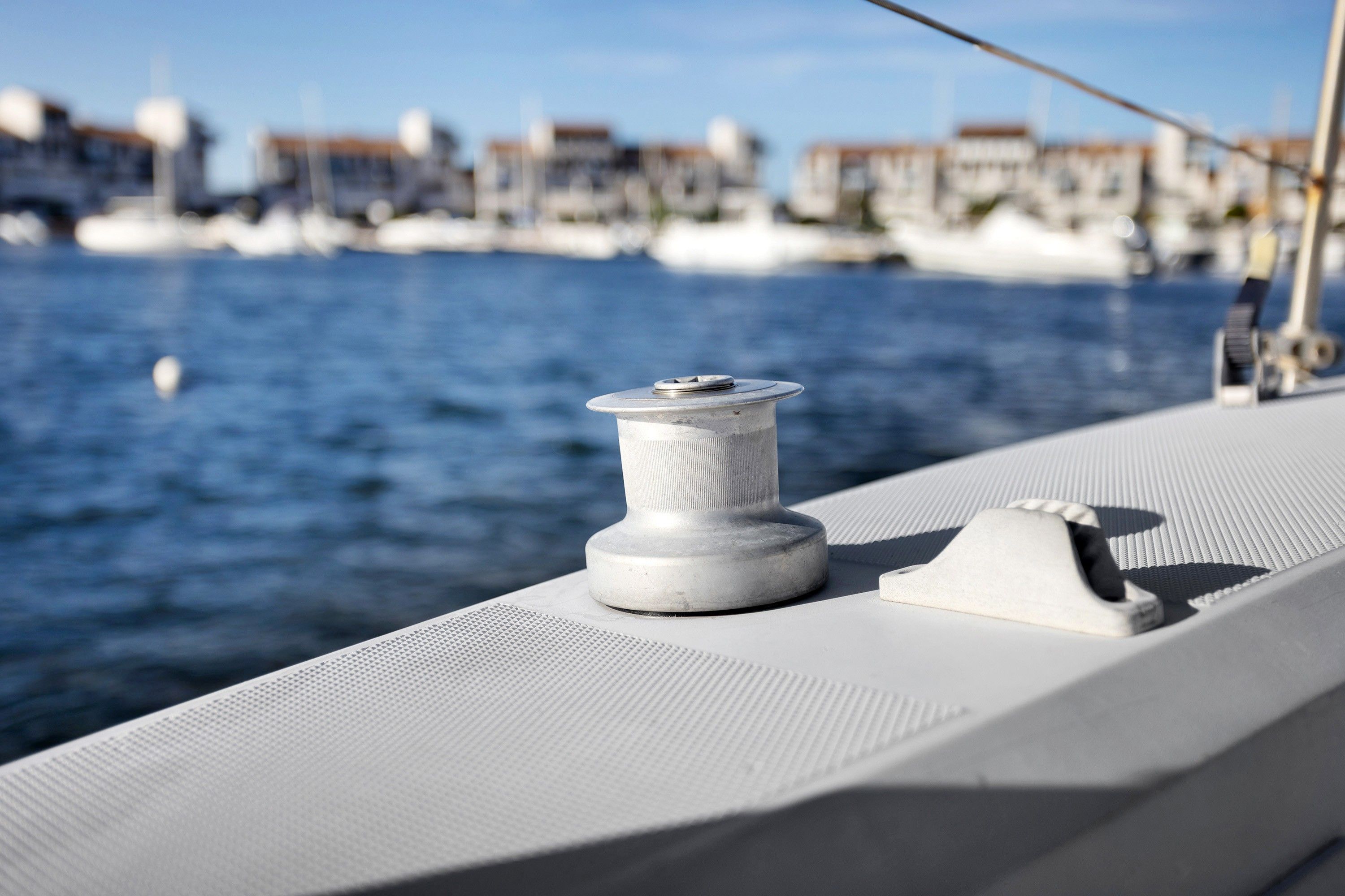 Um close-up do corrimão de um barco, com um carretel de corda branco e um crachá de metal.