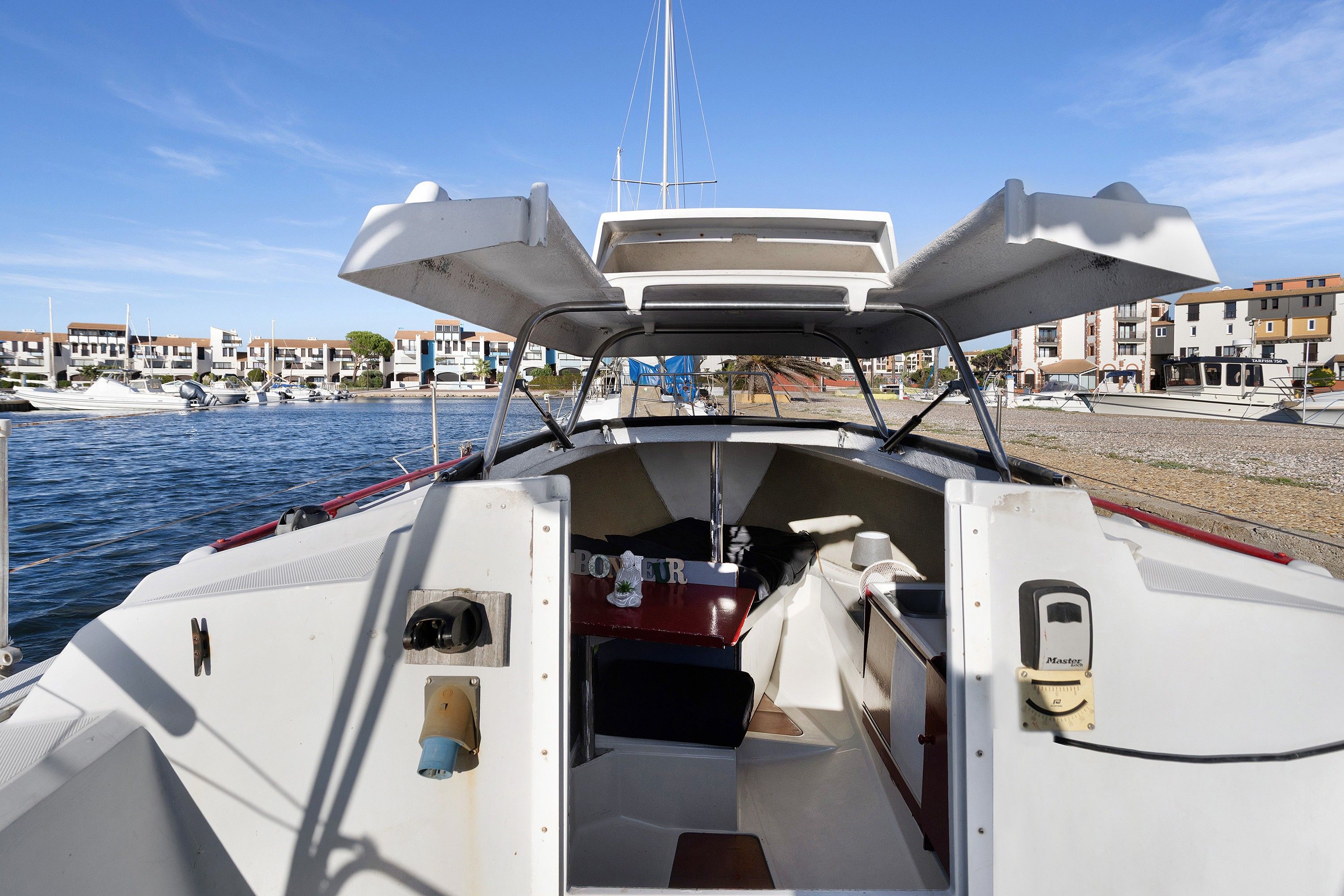 A boat's interior with a steering wheel, a small table, and a canopy overhead.