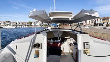 A boat's interior with a steering wheel, a small table, and a canopy overhead.