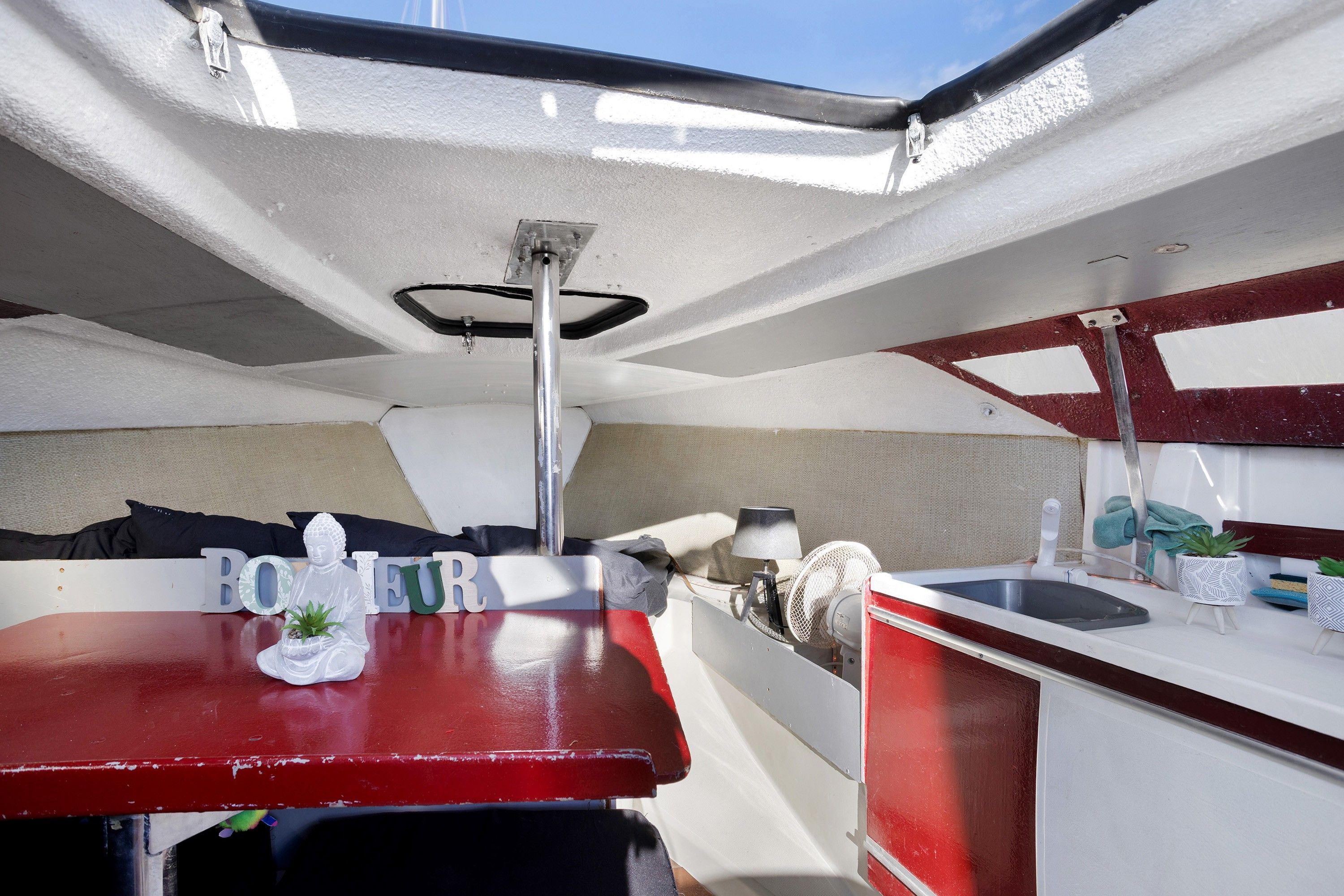 A compact boat interior with a kitchenette, a small seating area, and a window.