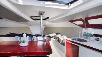 A compact boat interior with a kitchenette, a small seating area, and a window.