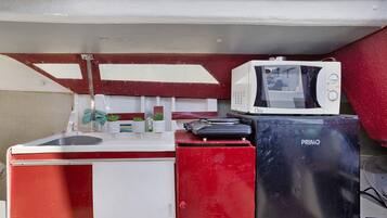A compact kitchenette with a sink, a microwave, and a small refrigerator.