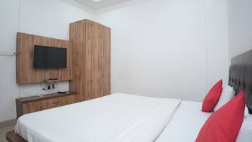 Ein Schlafzimmer mit einem Bett, einem Holzschrank, einem an der Wand montierten Fernseher und einem Nachttisch.