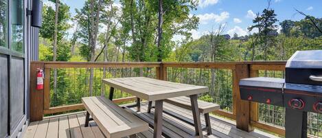 An outdoor deck with a picnic table and a barbecue grill.