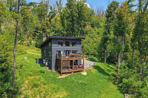 A modern cabin with a deck, surrounded by a forest. - Indoor Pool, Hot Tub & Mountain Views Near Pigeon Forge (Sevierville)