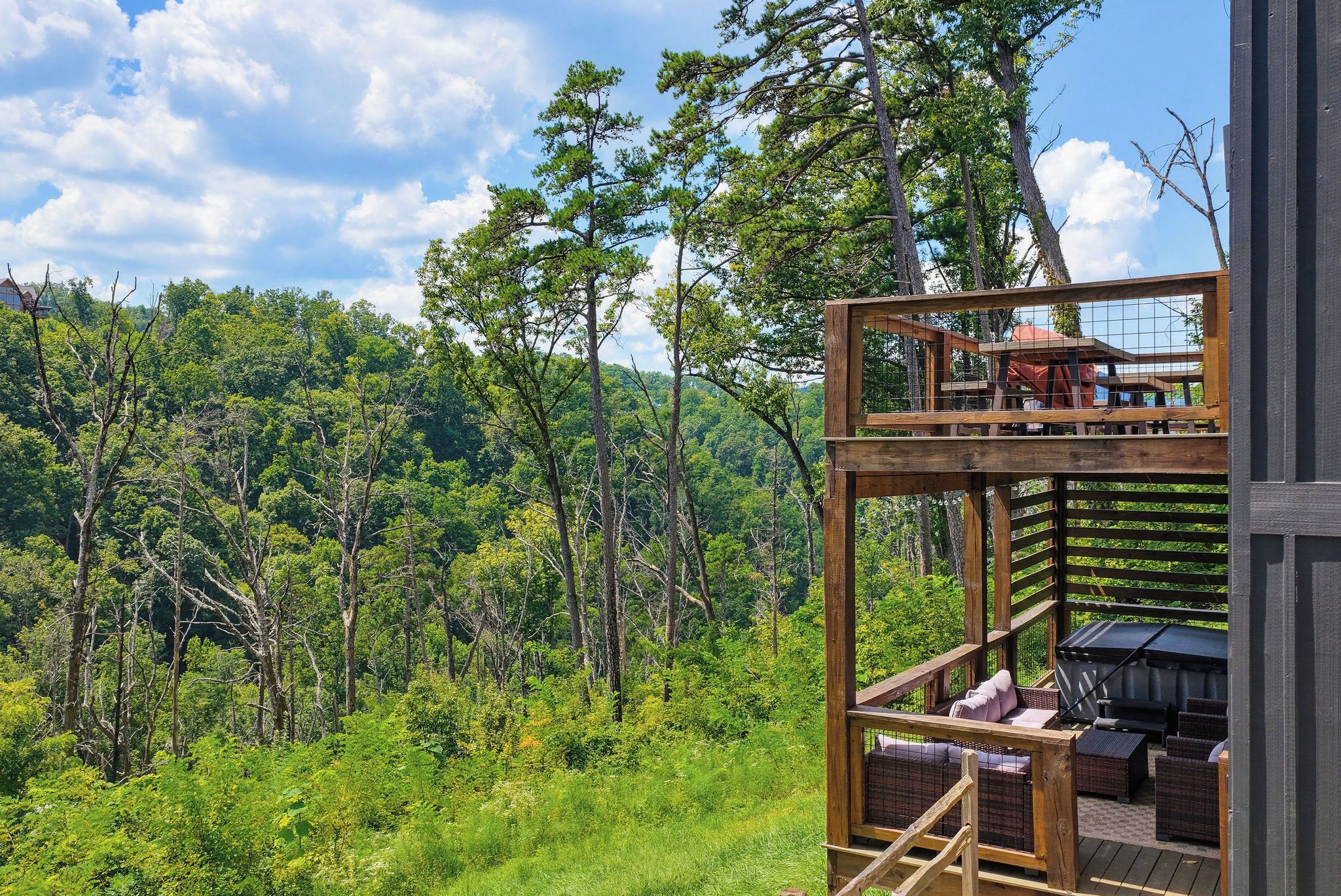 A wooden deck with outdoor furniture, overlooking a forested area.