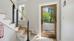A staircase with wooden steps and a metal handrail, leading to a door with a view of a road and trees. - Indoor Pool, Hot Tub & Mountain Views Near Pigeon Forge (Sevierville)