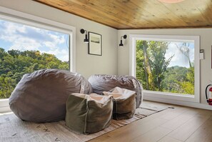 Een kamer met een groot raam, een houten plafond en een brandblusser aan de muur.