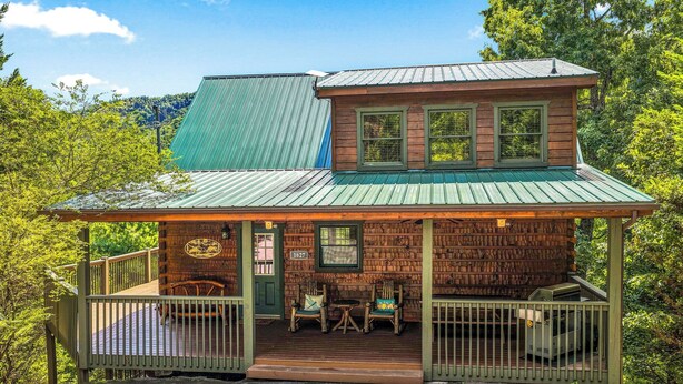 Une cabane avec une véranda, deux fenêtres et une porte.