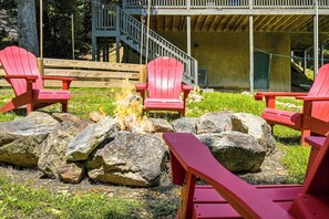 A fire pit with rocks and red Adirondack chairs arranged around it. - Smoky Mountain Views, Hot Tub & Game Loft Retreat (PIGEON FORGE)