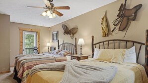 Une chambre avec deux lits, un ventilateur de plafond, des lampes fixées au mur et une fenêtre avec des stores.