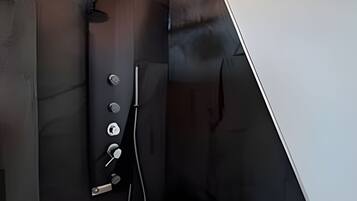 A modern shower with a handheld showerhead and a wall-mounted control panel.