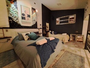A hotel room with a bed, two bedside tables, a wall-mounted lamp, and a large rug. - Okeyloft 2 Coyhaique (Coyhaique)