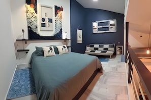 A modern bedroom with a bed, a sofa, a wall-mounted TV, and a unique wall art piece.