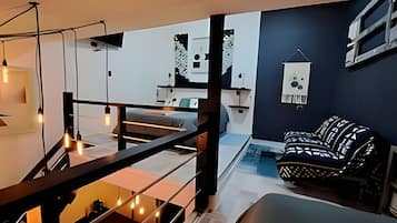 A modern interior with a staircase, a sofa, and a hanging light fixture.