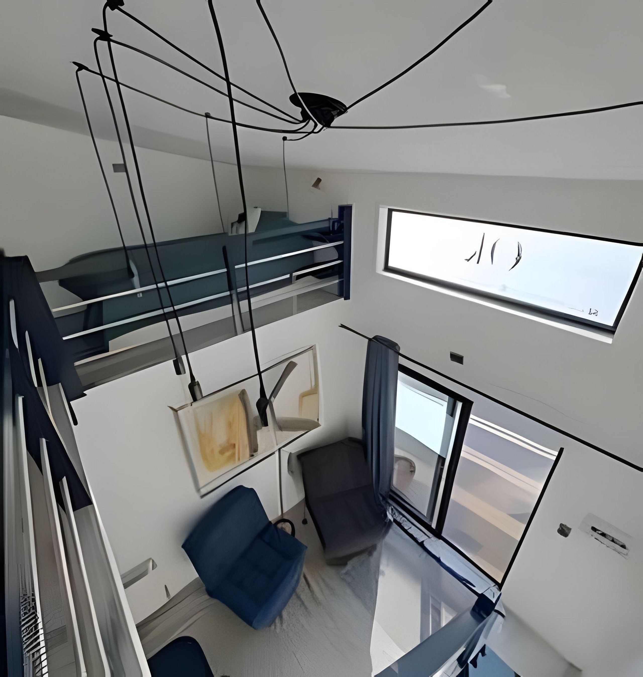 A modern interior with a bunk bed, a desk, a chair, and a large window.