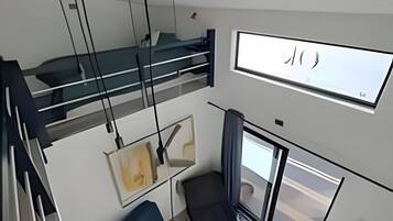 A modern interior with a bunk bed, a desk, a chair, and a large window.