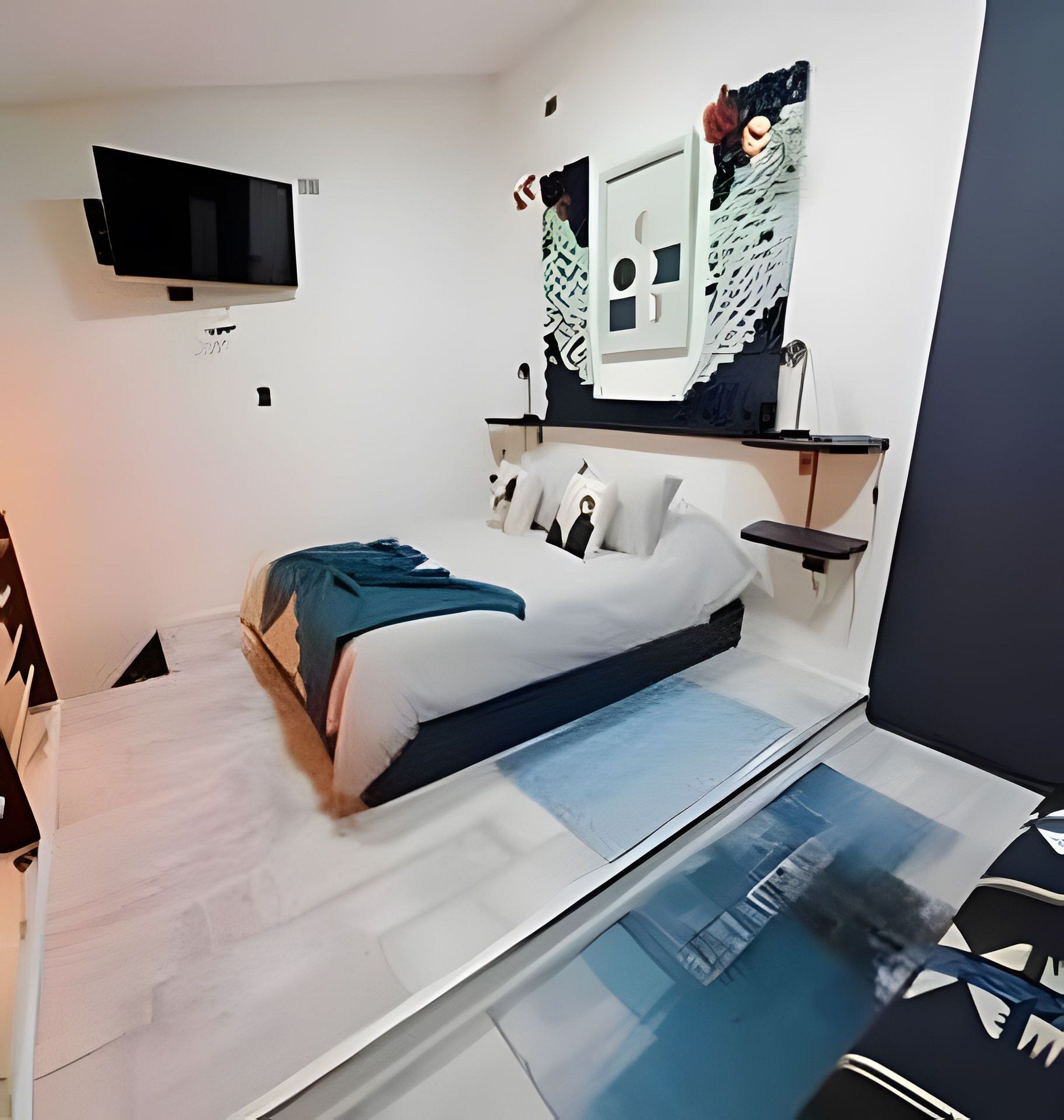 A modern bedroom with a bed, a flat-screen TV mounted on the wall, and a unique wall art piece.