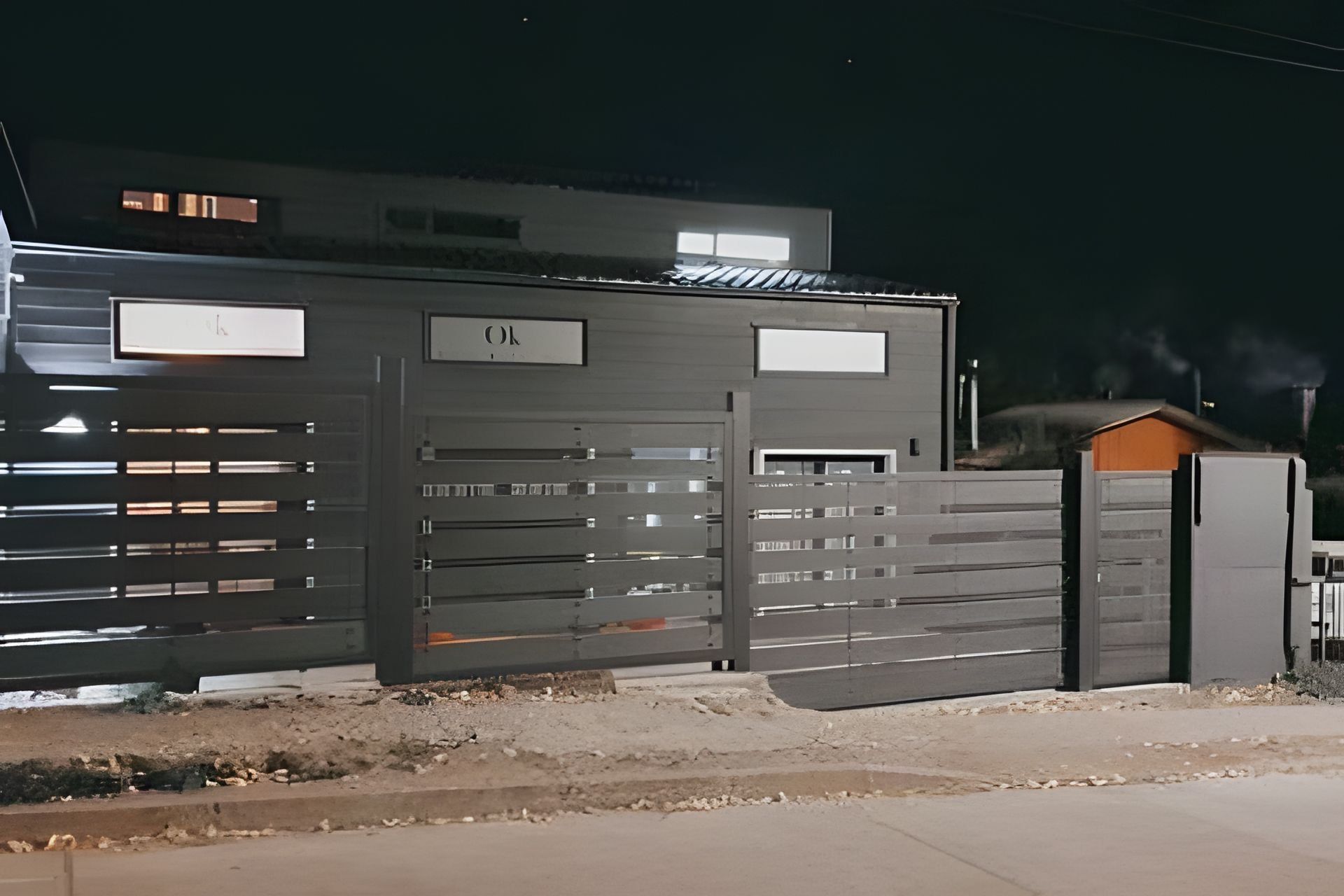 A gated industrial building with a sign that reads 'OK' and a smaller sign with a letter 'K'.