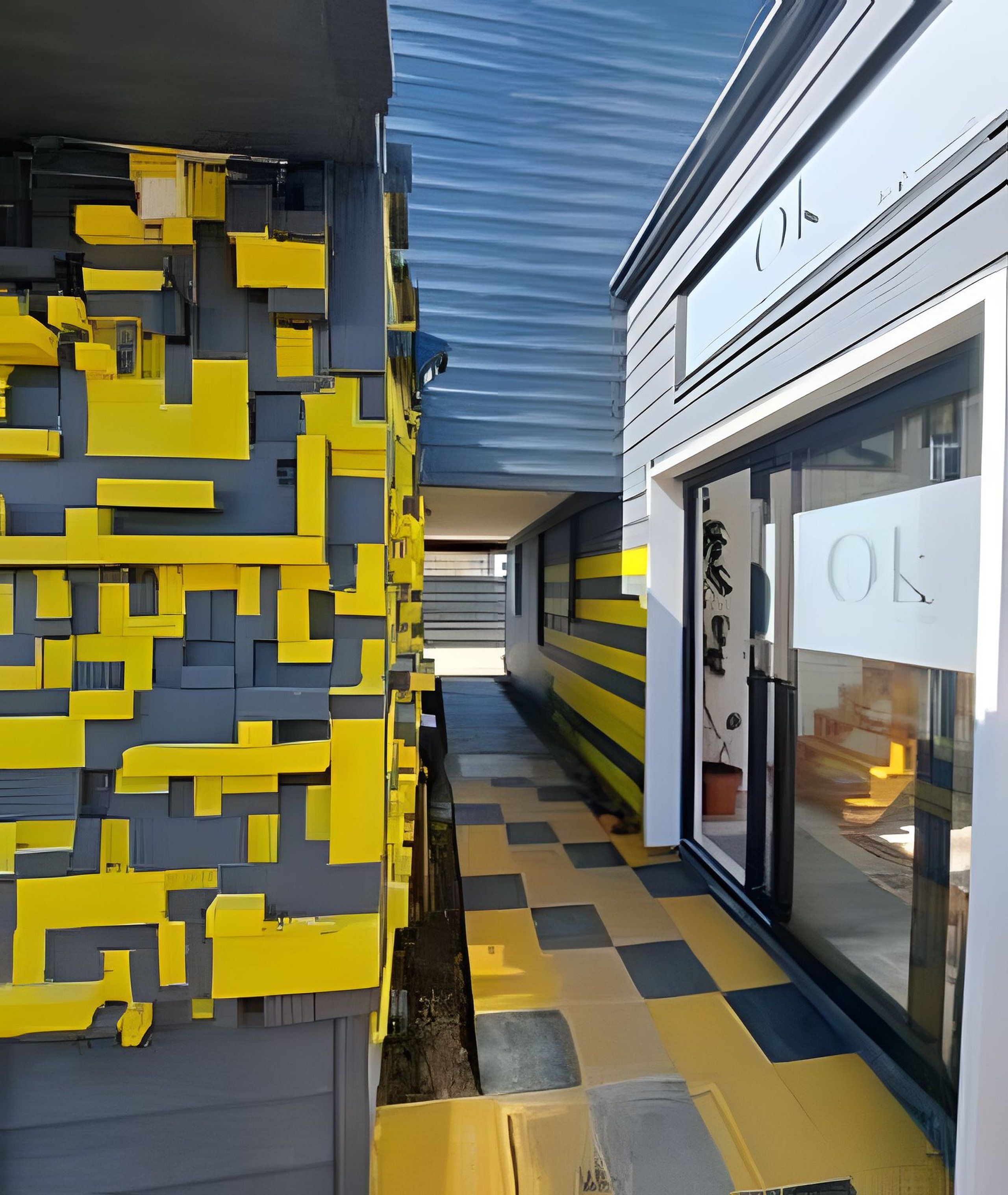 A corridor with a geometric wall pattern and a checkered floor, leading to a building with a glass facade and signage.