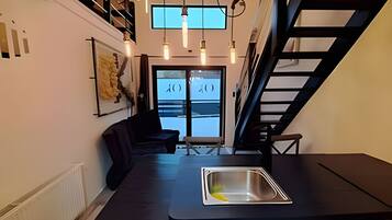 A modern kitchen with a built-in sink, a dark countertop, and a staircase leading to an upper level.