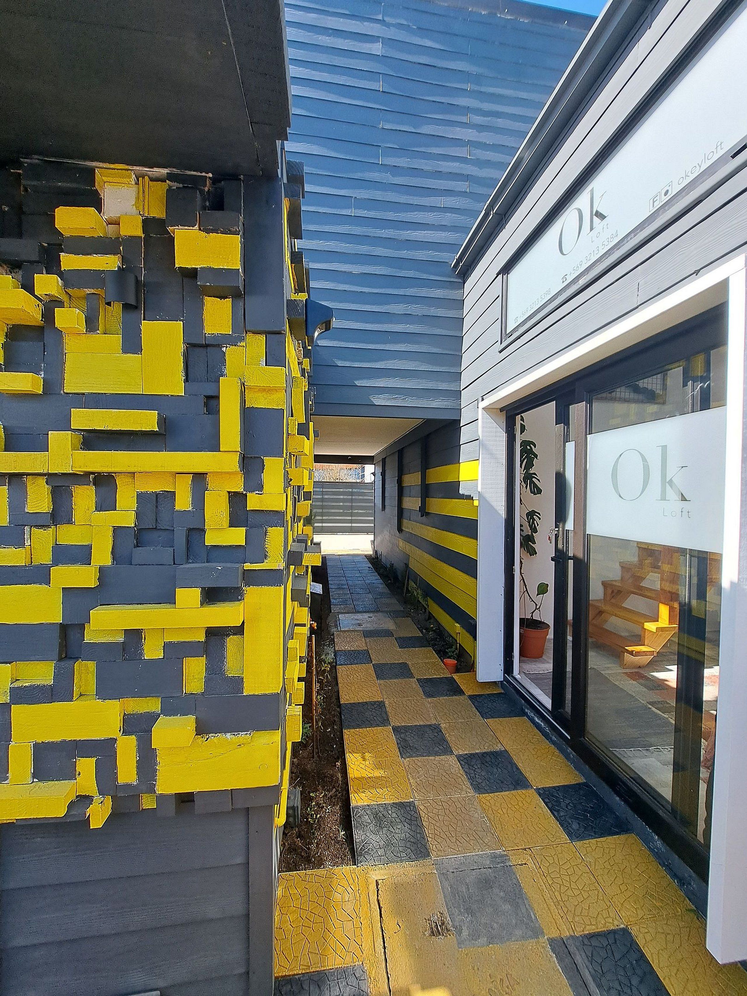 A building with a yellow and black patterned wall, a checkered floor, and a sign with 'Ok' on it.