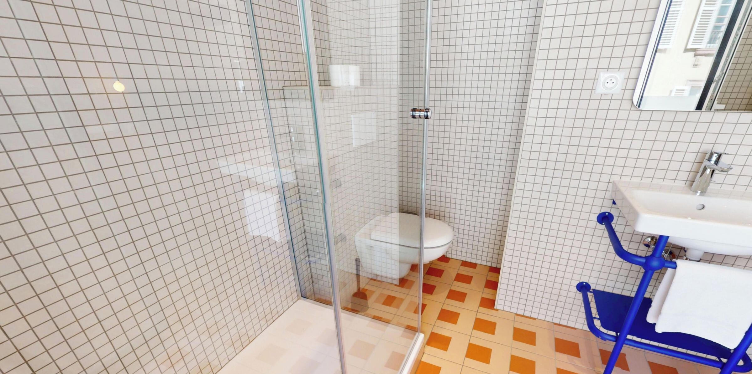 A bathroom with a glass-enclosed shower, a white toilet, and a blue chair.