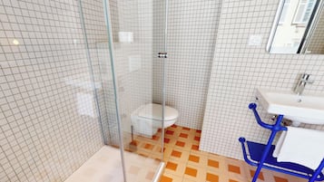 A bathroom with a glass-enclosed shower, a white toilet, and a blue chair.
