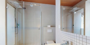Ein modernes Badezimmer mit Duschkabine aus Glas, einem weißen Waschbecken und einem großen Spiegel.