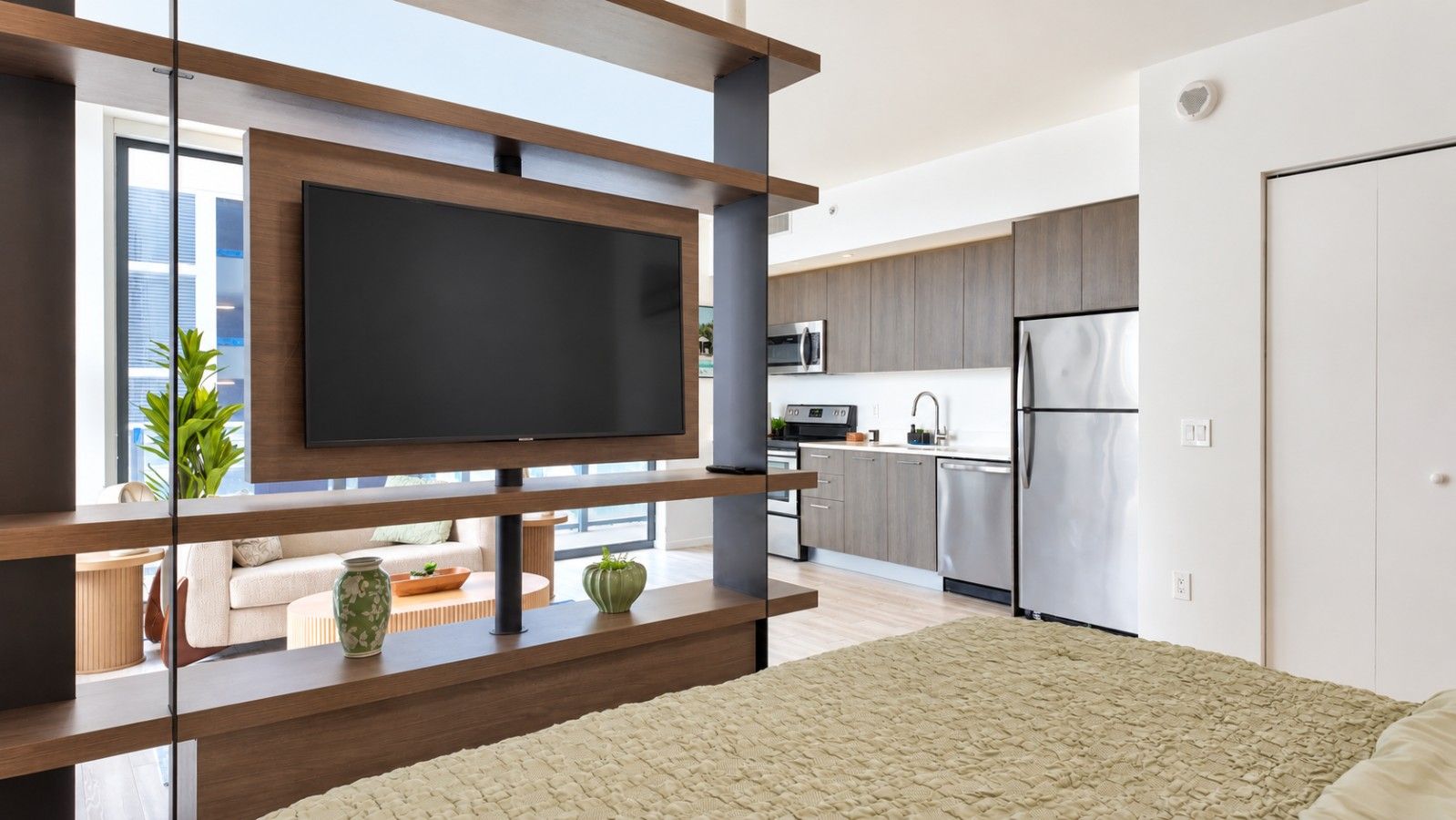Una sala de estar moderna con un televisor de pantalla plana grande, una zona de cocina con electrodomésticos de acero inoxidable y un rincón de descanso acogedor con un tapete estampado.
