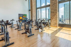 Ein Fitnessraum mit Ergometer, einer an der Wand befestigten Übungsball und einem Gewichthebergestell.
