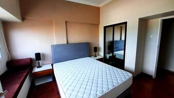 Um quarto com cama, mesas de cabeceira, espelho e guarda-roupa.
