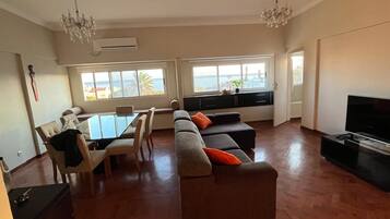 A spacious living area with a dining table, sofas, and a TV.
