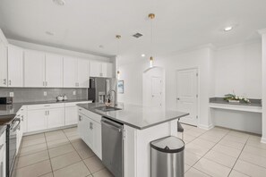 A modern kitchen with white cabinetry, a stainless steel refrigerator, a dishwasher, and a trash can. - 3 Themed BRs - Heated Pool, Spa & Kids Playroom (Davenport)