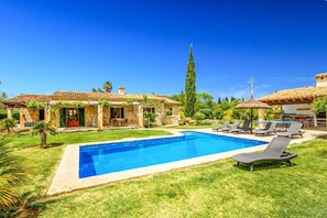 A swimming pool with lounge chairs, a stone building, and a tall tree. - Villa 'Roig' with Private Pool, Wi-Fi and Air Conditioning (Illes Balears)