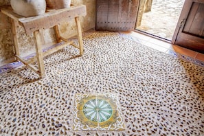 A room with a textured floor, a wooden table with pottery, and a patterned tile in the center. - Villa 'Roig' with Private Pool, Wi-Fi and Air Conditioning (Illes Balears)