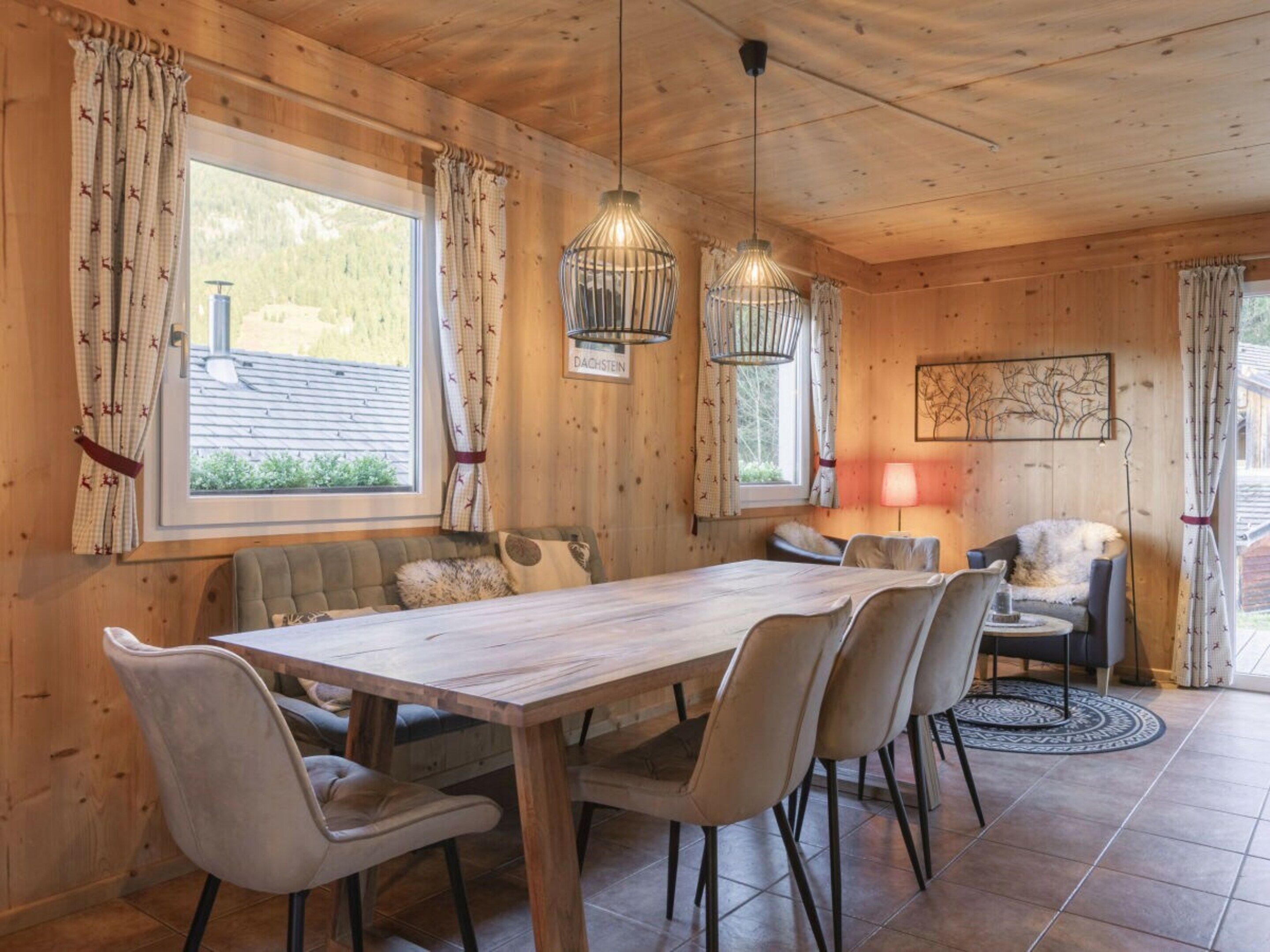 A wooden interior with a dining table, chairs, a sofa, and a lamp.