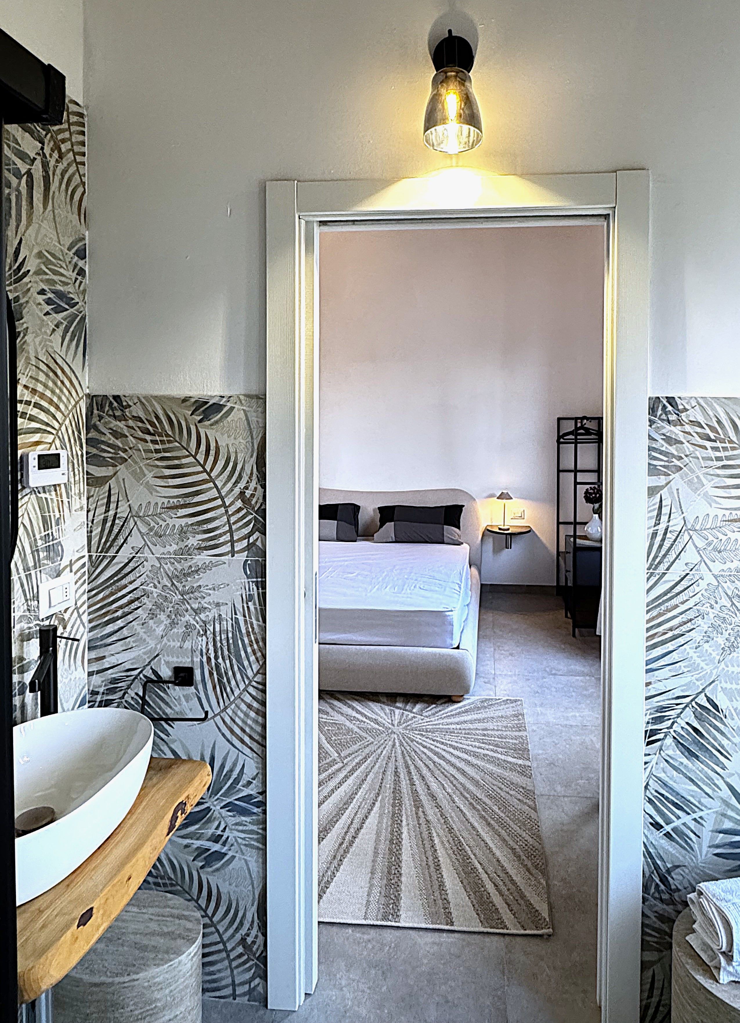A bedroom with a bed, bedside tables, a nightstand, and a mirror.