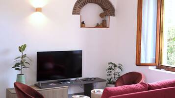 Una sala de estar con un televisor de pantalla plana, sofás rojos, una planta en maceta y un arco de ladrillo.