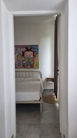 Un dormitorio con una cama, un cuadro, una mesita de noche y una alfombra.