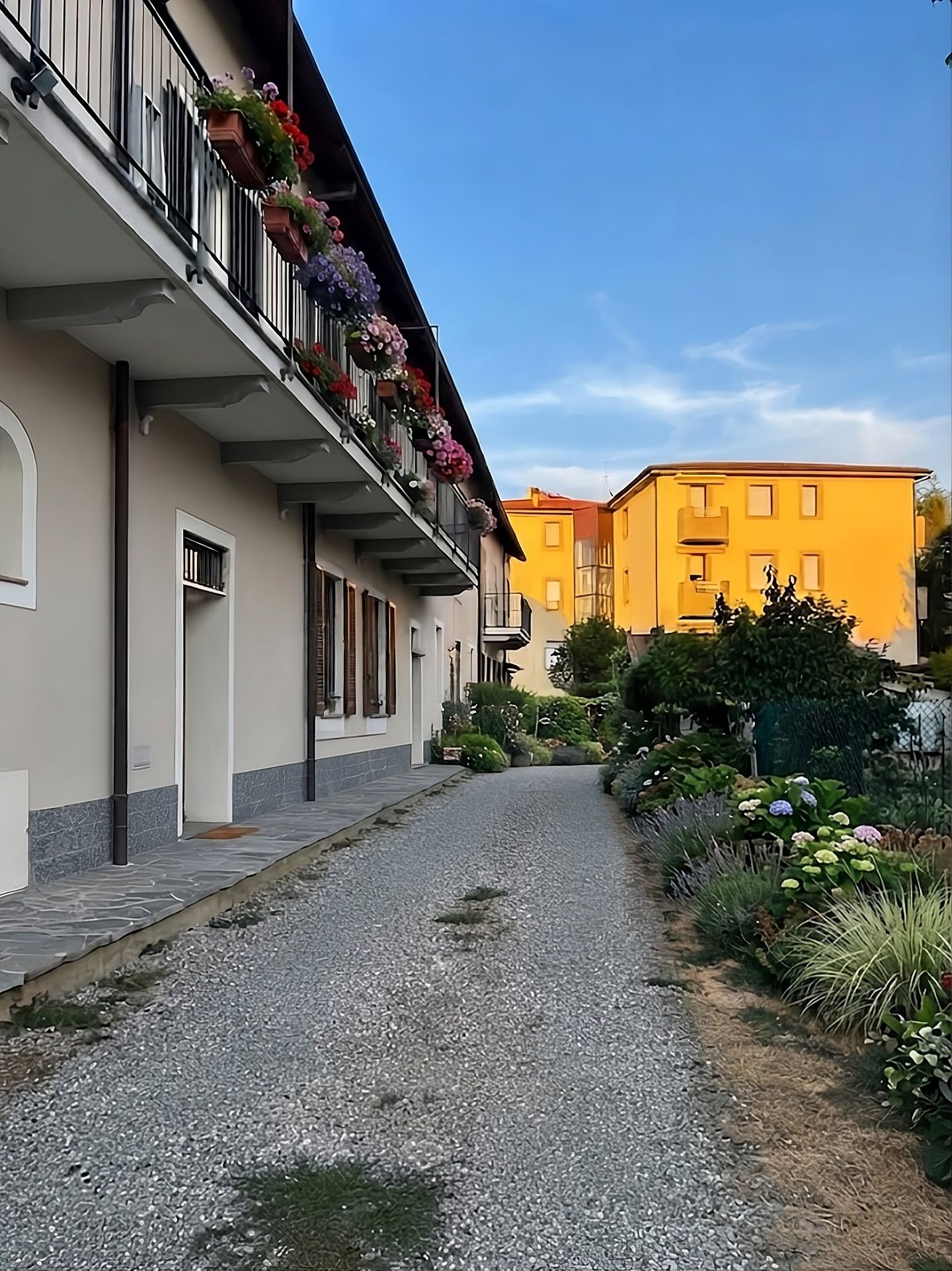 Una stretta via fiancheggiata da edifici, uno dei quali con un balcone decorato di fiori.