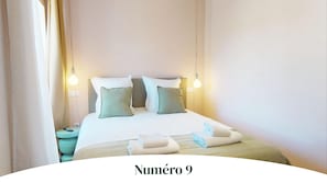 A hotel room with a bed, bedside tables, and two wall-mounted light fixtures. - Apartment No. 9 (1 bedroom) - Champ Residence (Colmar)