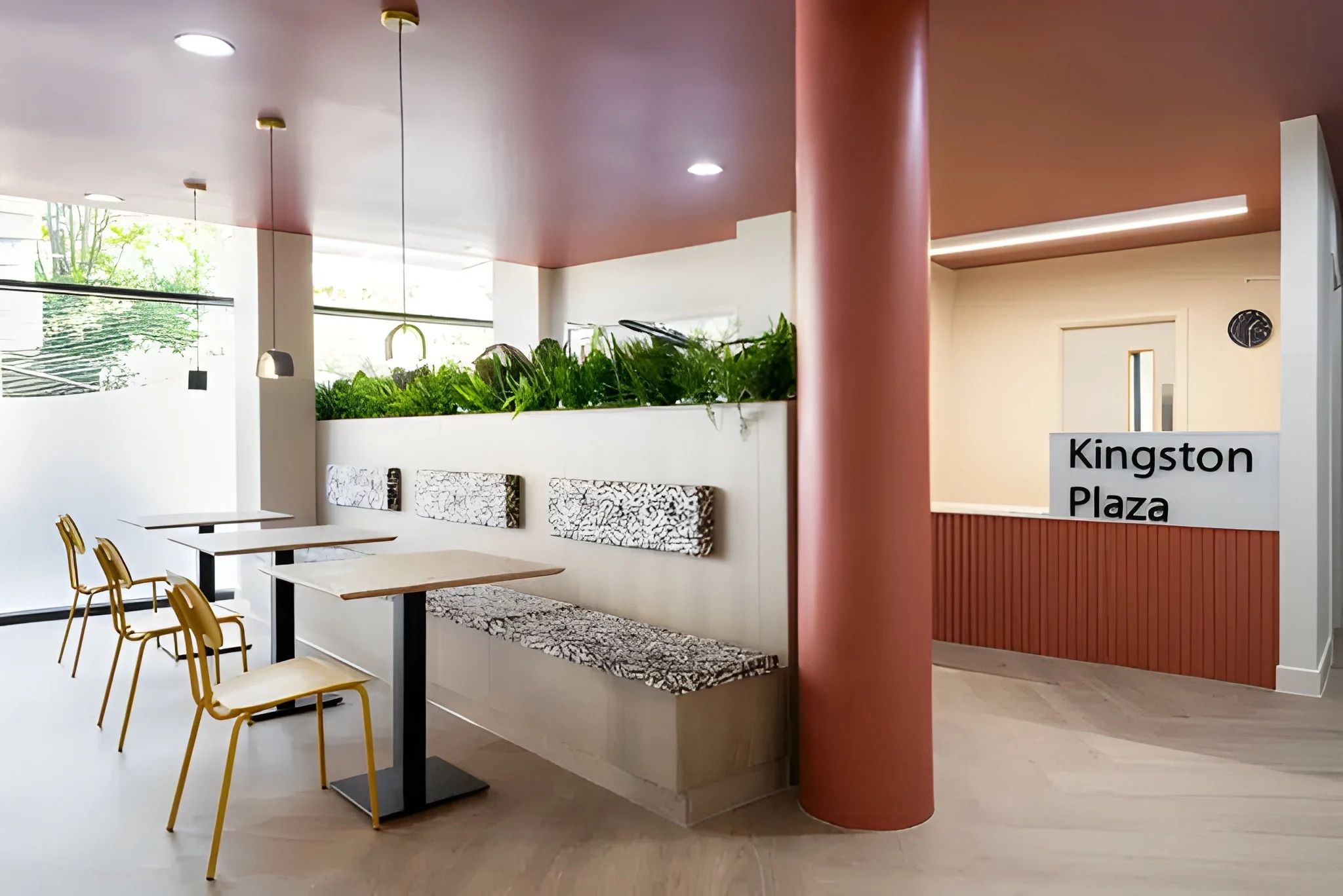 A modern interior with a seating area, a reception desk, and a sign reading 'Kingston Plaza'.